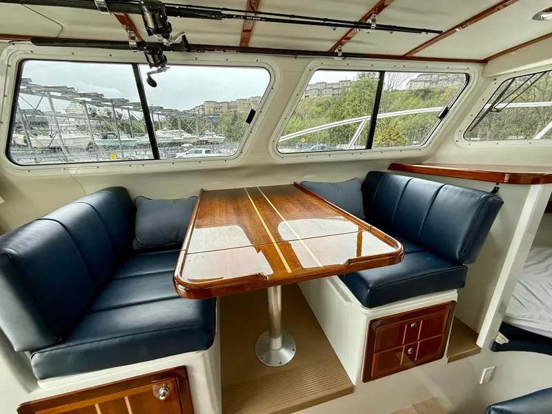 Slide: The Image of Interior of 2014 Ocean Sport Legacy #4 boat with blue seating and wooden table. - 14