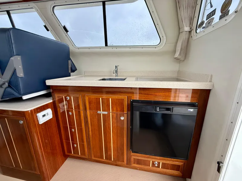 Slide: The Image of 2014 Ocean Sport Legacy #4 boat interior with wooden cabinetry and compact kitchenette. - 15