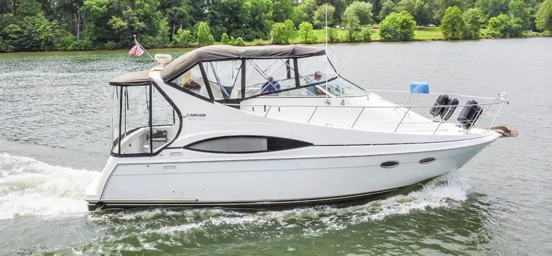 Slide: The Image of 2002 Carver 350 MARINER cruising on a lake with lush green shoreline. - 4