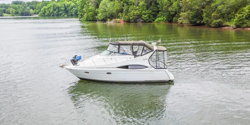 Slide: The Image of 2002 Carver 350 MARINER yacht cruising on a serene lake surrounded by lush greenery. - 6