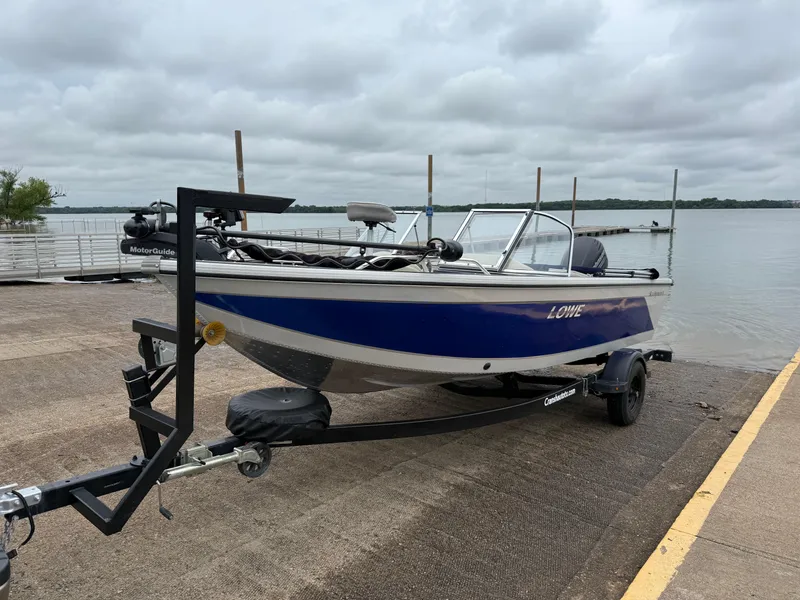 The Image of 2002 Lowe Sea Nymph V Series FM 180 boat on trailer by a lake. - 0