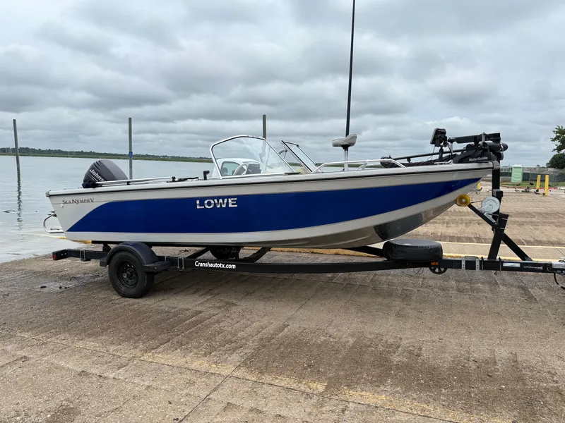 Slide: The Image of 2002 Lowe Sea Nymph V Series FM 180 boat on trailer, parked by a lake. - 10