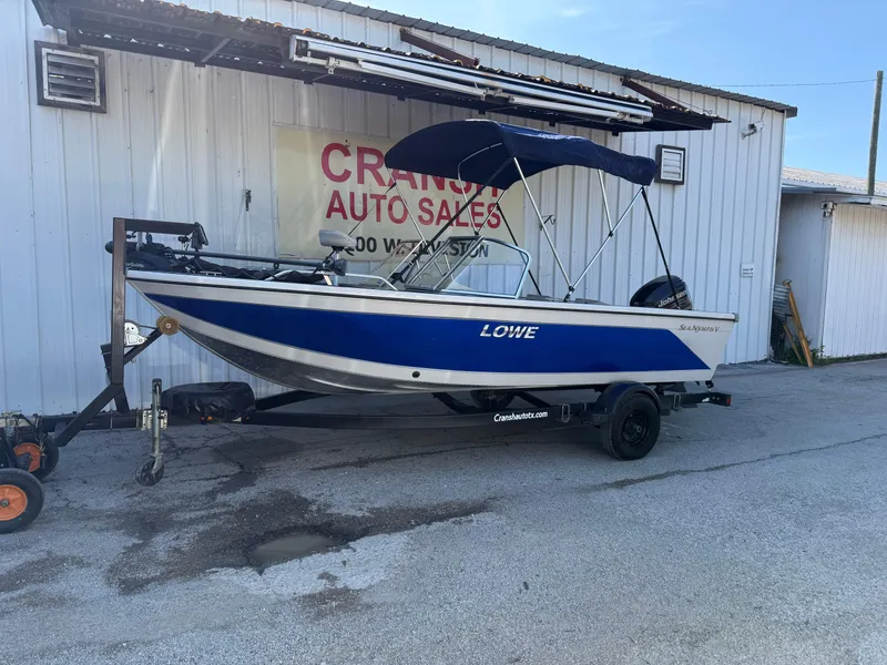 Slide: The Image of Boat trailer with 2002 Lowe Sea Nymph V Series FM 180, parked near a lake on a cloudy day. - 15