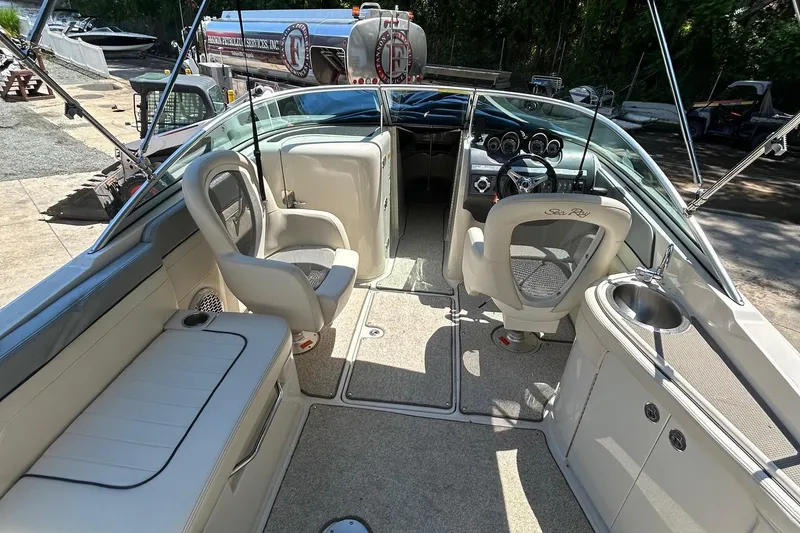 Slide: The Image of 2010 Sea Ray 260 Sundeck interior with seating and steering console, docked outdoors. - 10