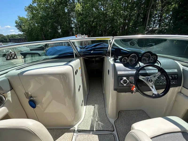 Slide: The Image of 2010 Sea Ray 260 Sundeck interior with steering wheel and dashboard, surrounded by lush greenery. - 7