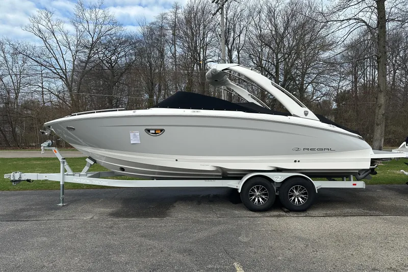 Slide: The Image of 2026 Regal LS9 boat on trailer, parked outdoors with trees in the background. - 0