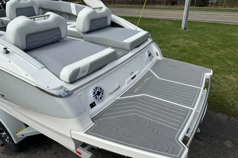 Slide: The Image of 2026 Regal LS9 boat with gray seating and swim platform, parked on grass. - 3