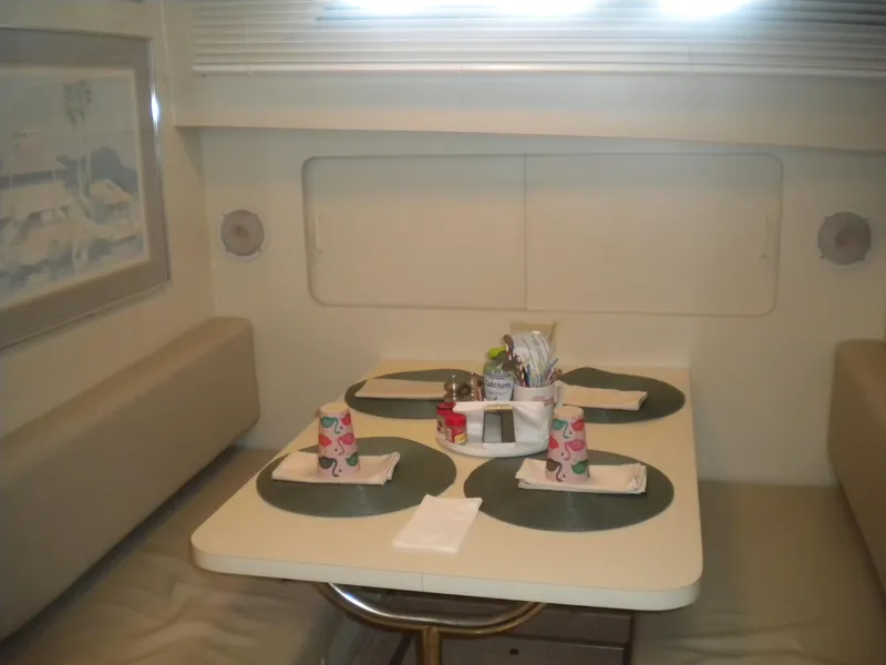 Slide: The Image of Dining area in 1987 Hatteras 53 Motor Yacht with table settings and cushioned seating. - 24