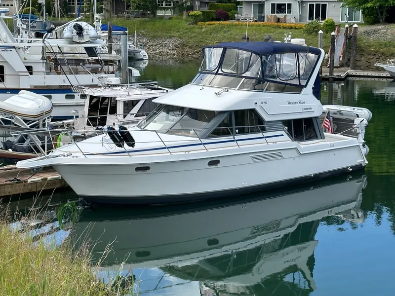 Slide: The Image of 1996 Carver Voyager boat docked in a marina, featuring a sleek white design and blue canopy. - 1