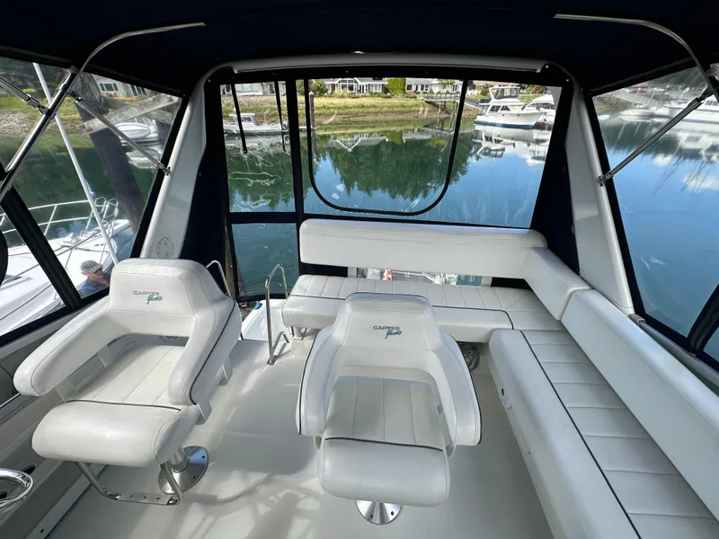 Slide: The Image of Interior of a 1996 Carver Voyager boat with white seating and scenic marina view. - 17