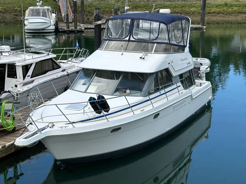 Slide: The Image of 1996 Carver Voyager boat docked in a marina, featuring a sleek white design and blue canopy. - 2