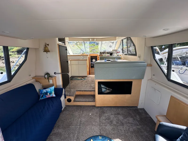 Slide: The Image of Interior of a 1996 Carver Voyager yacht, featuring a cozy seating area and helm. - 27