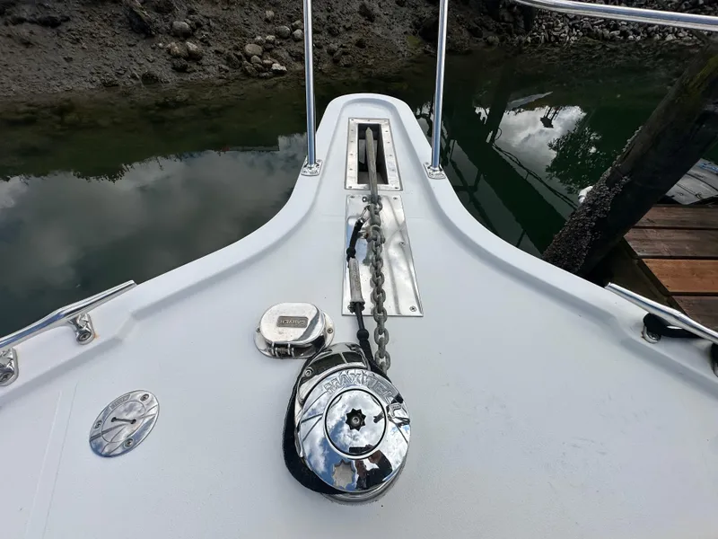 Slide: The Image of Bow of 1996 Carver Voyager with anchor chain and winch by the water. - 6