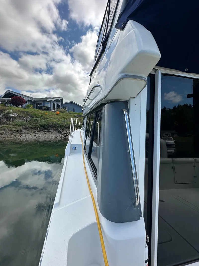 Slide: The Image of 1996 Carver Voyager boat docked by a lakeside house under a cloudy sky. - 8