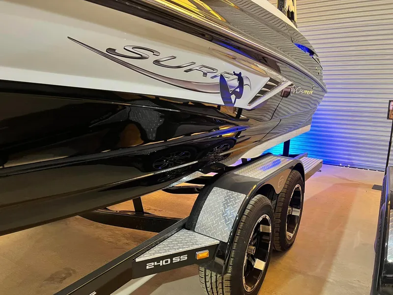 Slide: The Image of 2024 Crownline 240SS Surf boat on trailer in garage setting. - 3