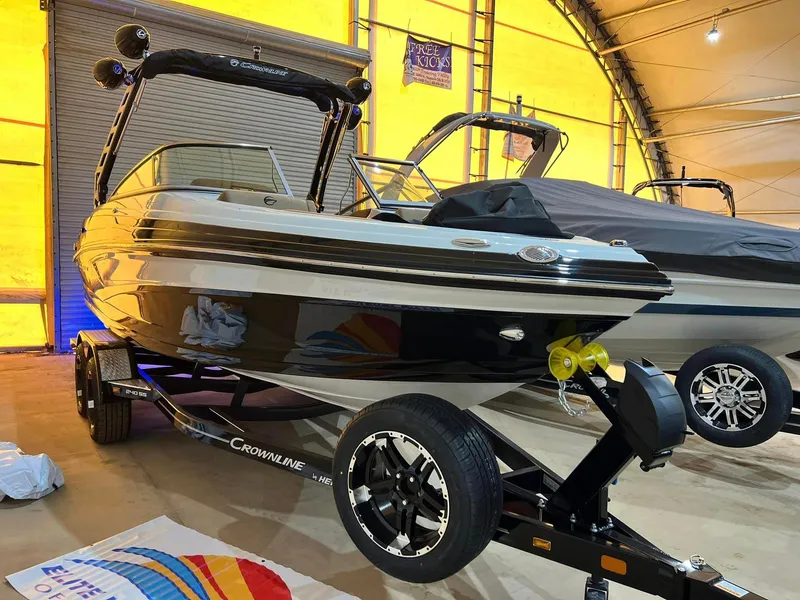 Slide: The Image of 2024 Crownline 240SS Surf boat on trailer in indoor showroom. - 5