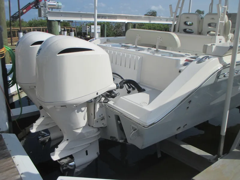 Slide: The Image of 2018 Cobia 301 Center Console boat docked with fishing rods, in a marina setting. - 4