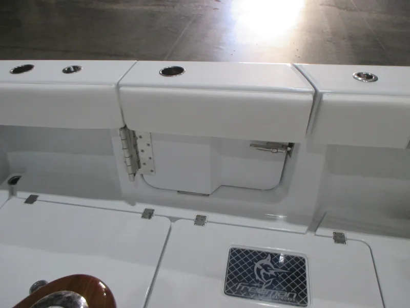 Slide: The Image of 2018 Cobia 301 Center Console boat interior with seating and storage, docked by the water. - 9