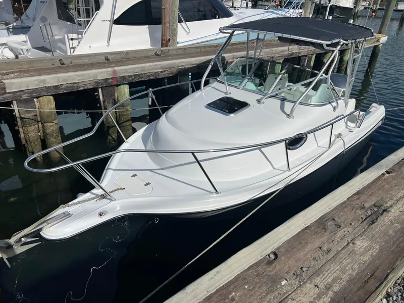 Slide: The Image of 2005 Sailfish 234 WAC boat docked at a marina, featuring a sleek white design. - 2