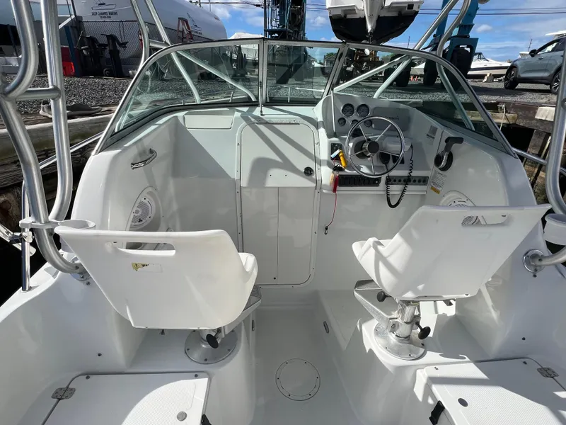 Slide: The Image of 2005 Sailfish 234 WAC boat cockpit with dual white seats and steering wheel. - 9