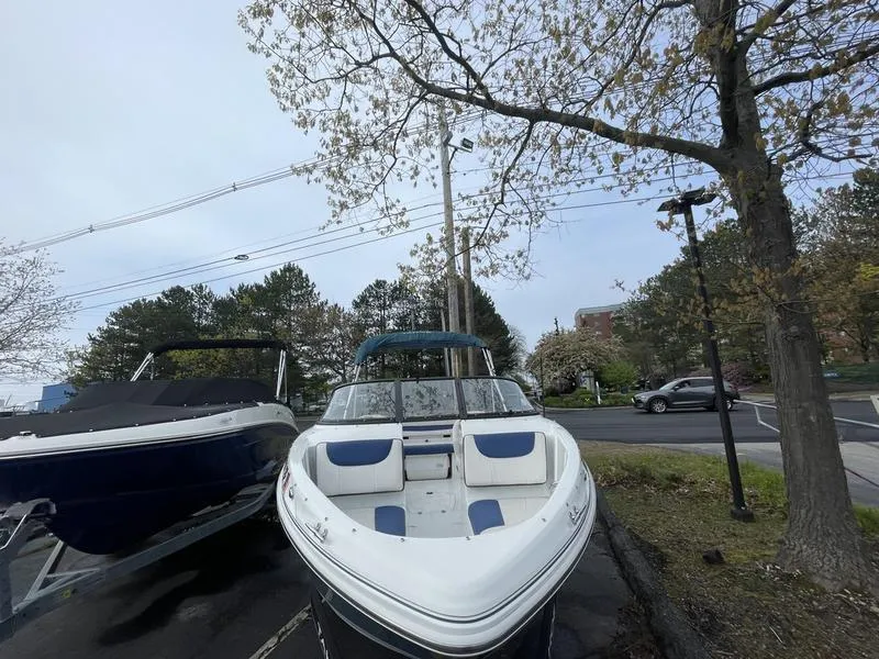Slide: The Image of 2019 Tahoe 500 TS boat parked outdoors near trees and road. - 7