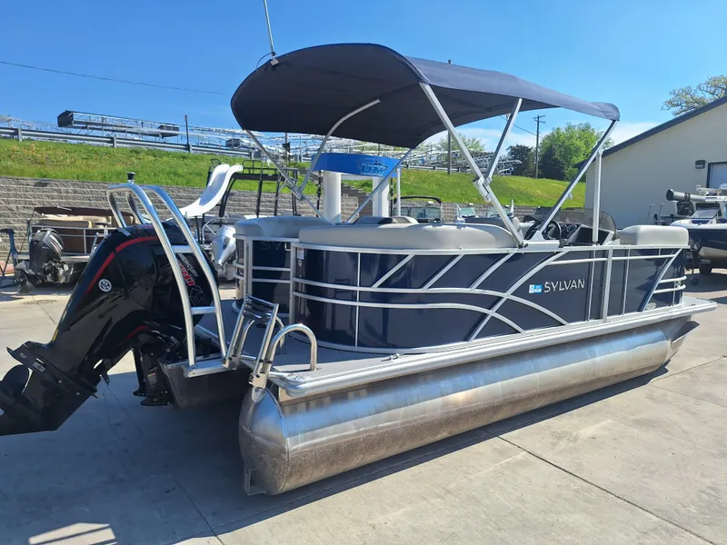 Slide: The Image of 2024 Sylvan Mirage Cruise 8520 CLZ DH pontoon boat with canopy, docked outdoors. - 2