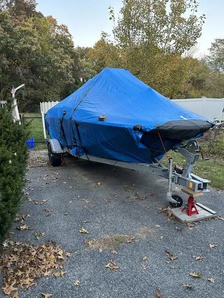 Slide: The Image of 2017 Bayliner Element F18 CC boat covered with blue tarp on trailer. - 2