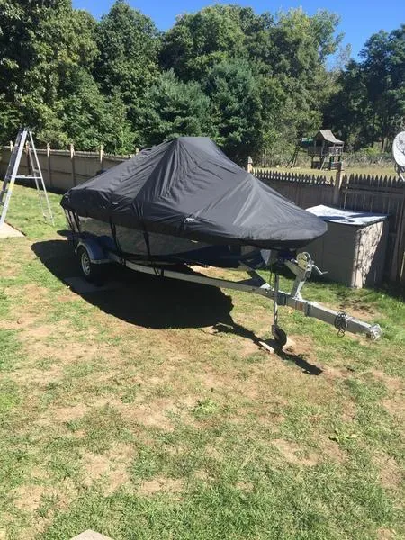 Slide: The Image of 2017 Bayliner Element F18 CC boat covered, parked on grass with trees in the background. - 6