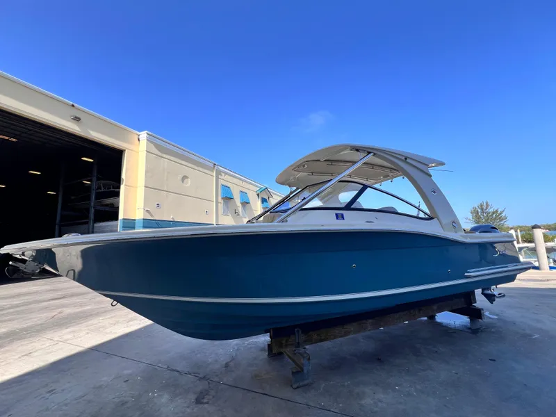 Slide: The Image of 2018 Scout 275 Dorado boat in a marina setting, blue hull, clear sky. - 1