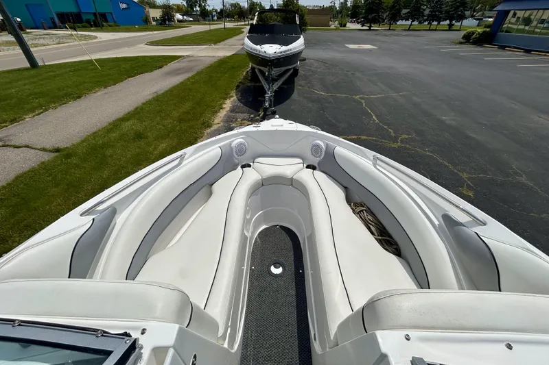 Slide: The Image of 2014 Rinker Captiva 246 BR boat with spacious seating, parked on a paved lot. - 11