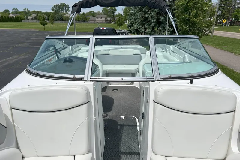 Slide: The Image of 2014 Rinker Captiva 246 BR boat interior with white seating and open windshield. - 12