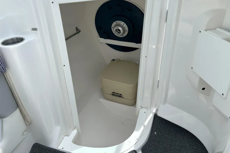 Slide: The Image of 2014 Rinker Captiva 246 BR boat interior with compact toilet and storage space. - 13