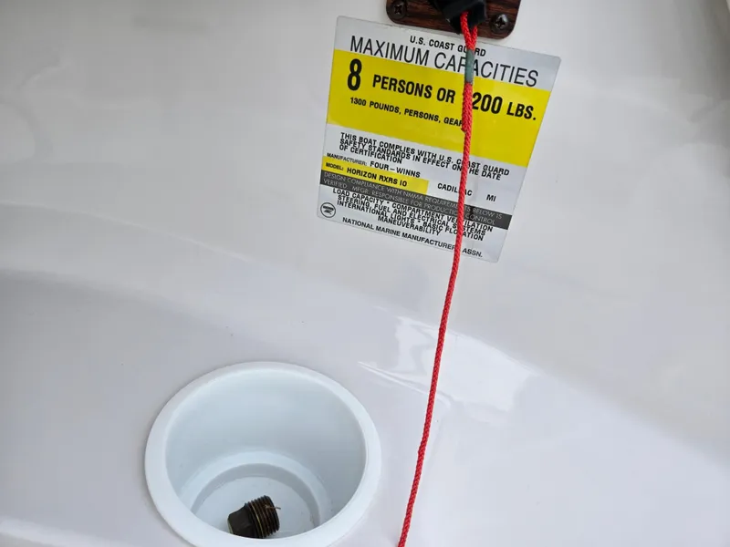 Slide: The Image of 1998 Four Winns Horizon RS RX capacity label, 8 persons or 1200 lbs, with red cord and drain plug. - 13