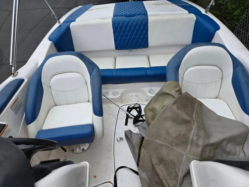 Slide: The Image of 2004 Yamaha Boats 210 LX interior with blue and white seating, covered equipment. - 10