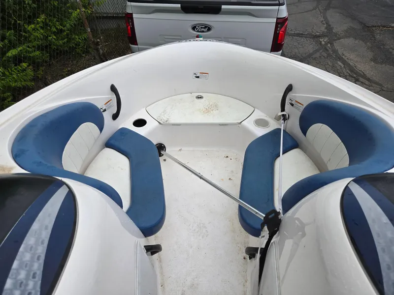 Slide: The Image of 2004 Yamaha Boats 210 LX interior with blue seating, parked near a Ford vehicle. - 19