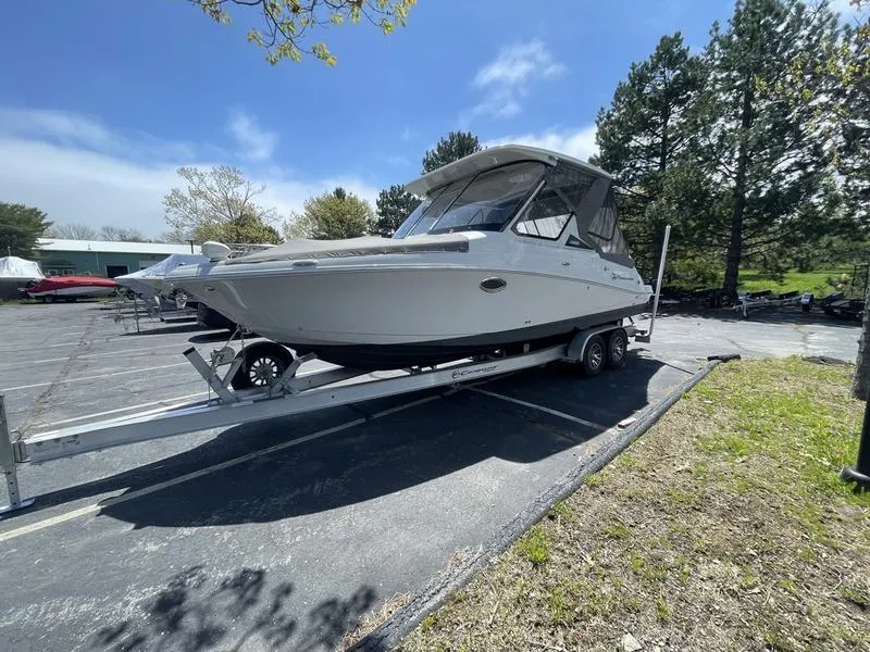 Slide: The Image of 2022 Finseeker 280 DC boat on trailer in parking lot, surrounded by trees. - 5