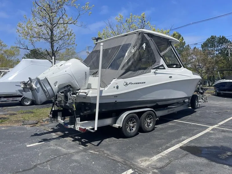 Slide: The Image of 2022 Finseeker 280 DC boat on trailer in parking lot, clear sky background. - 6