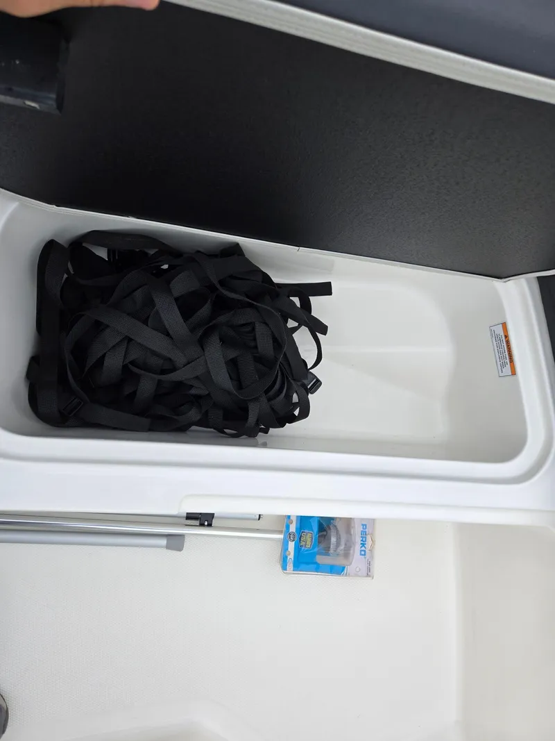 Slide: The Image of 2022 Bayliner Element M15 storage compartment with black straps and packaged item. - 14