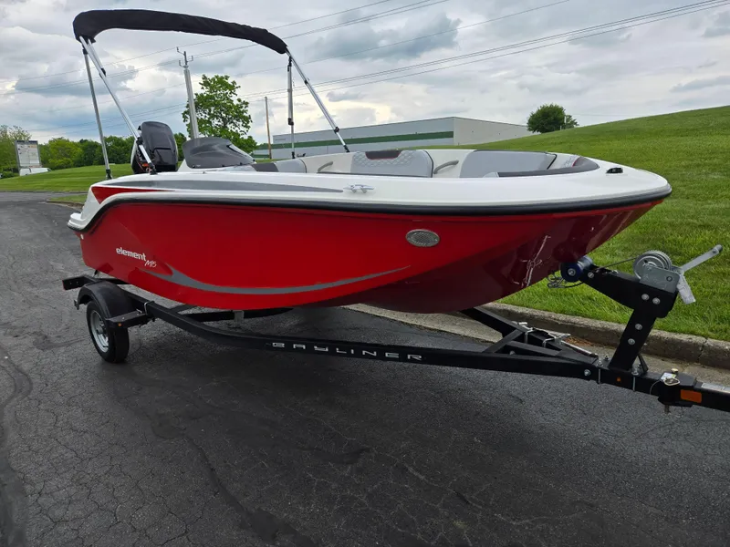Slide: The Image of 2022 Bayliner Element M15 boat in vibrant red on a trailer, parked outdoors. - 5