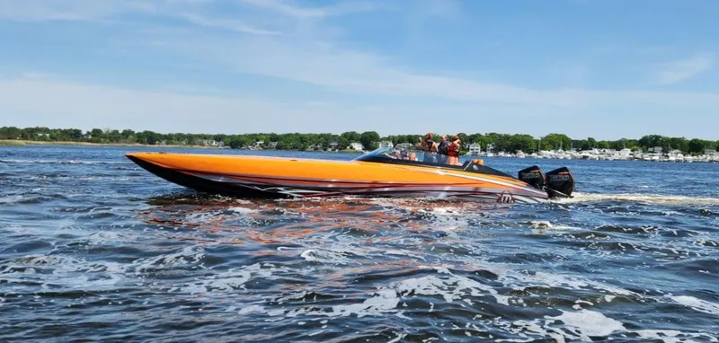 Slide: The Image of 2024 Mystic Powerboats C4000, orange speedboat cruising on a sunny day. - 0