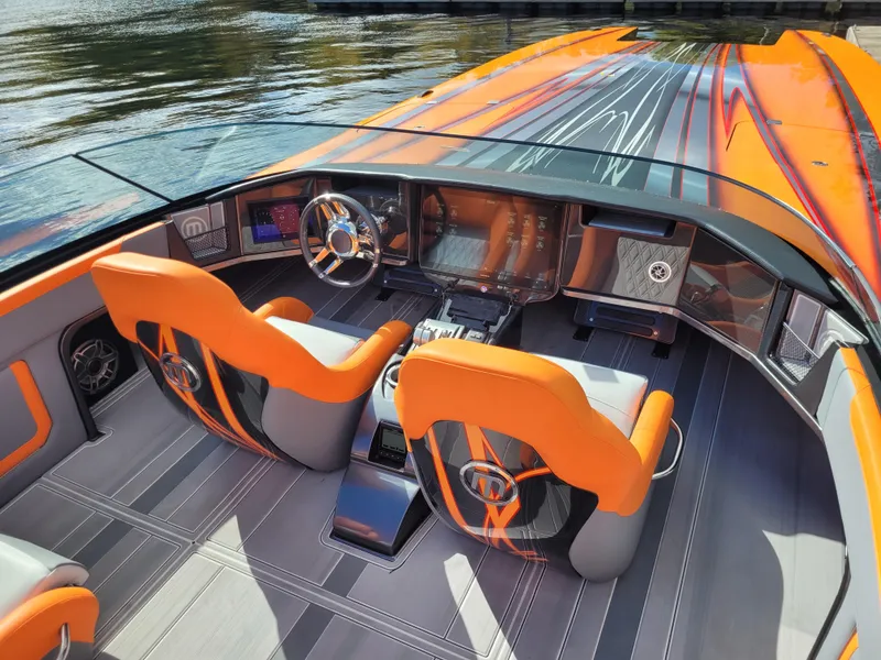 Slide: The Image of 2024 Mystic Powerboats C4000 cockpit with vibrant orange seats and sleek dashboard design. - 1