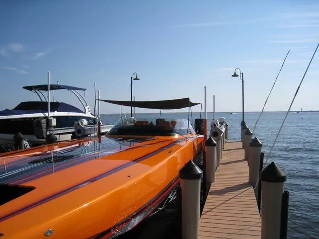 Slide: The Image of 2024 Mystic Powerboats C4000 docked, vibrant orange, sleek design, sunny day, calm waters. - 11