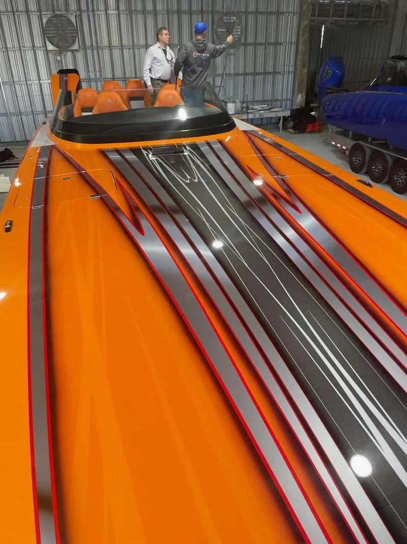Slide: The Image of 2024 Mystic Powerboats C4000 with vibrant orange and black design in a garage setting. - 13