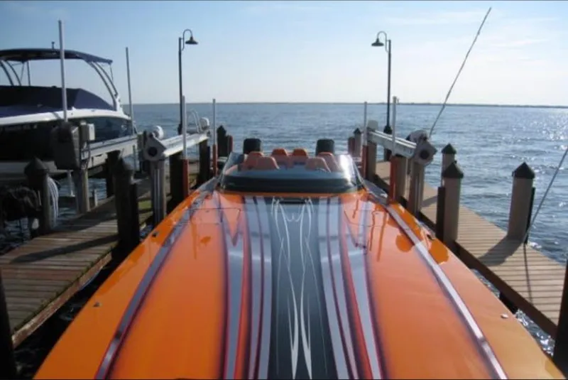 Slide: The Image of 2024 Mystic Powerboats C4000 docked, vibrant orange and black design, calm waters in the background. - 14