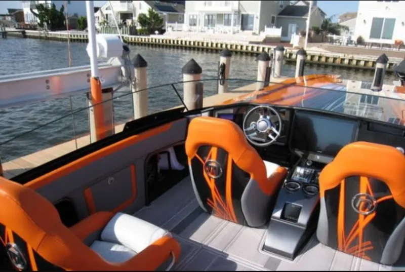 Slide: The Image of 2024 Mystic Powerboats C4000 cockpit with orange seats, sleek design, and waterfront view. - 16
