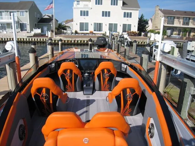 Slide: The Image of 2024 Mystic Powerboats C4000 with vibrant orange seating docked at a marina. - 2