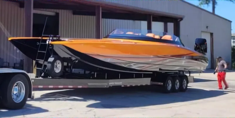 Slide: The Image of 2024 Mystic Powerboats C4000 in vibrant orange on a trailer outside a warehouse. - 4