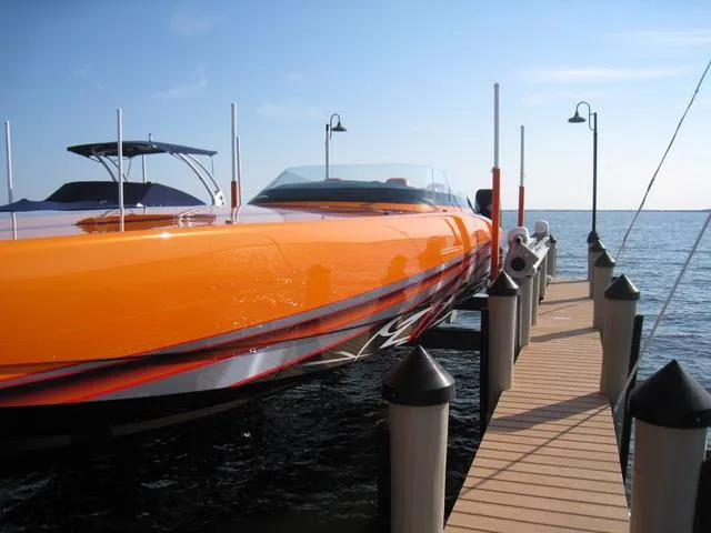 Slide: The Image of 2024 Mystic Powerboats C4000 in vibrant orange docked by a wooden pier. - 7