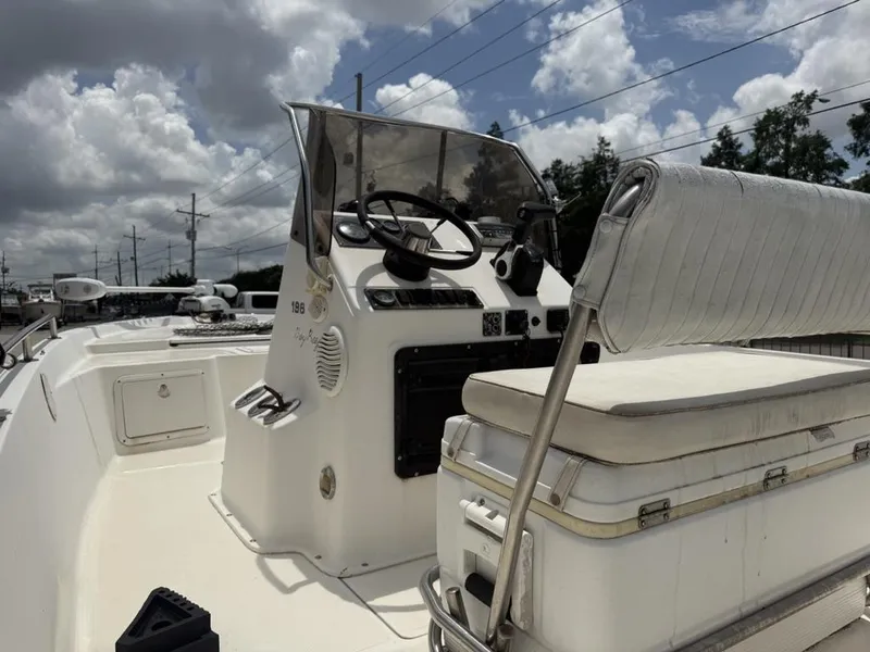 Slide: The Image of 2001 Key West 196 Bay Reef boat interior with steering console and seating under cloudy sky. - 4