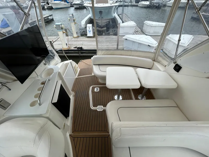 Slide: The Image of 2006 Cruisers Yachts 300 Express interior with white seating, wooden flooring, and marina view. - 24